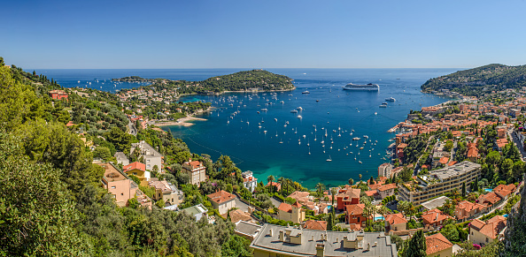 Ultra wide angle high level panorama of Villefranche bay, Nice, Cote d'Azur, France, showing Mont Boron to the West and Cap Ferat to the East, with the clear  turquoise meditaerannean sea in the bay under a clear blue sky