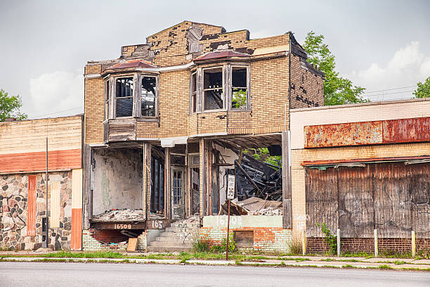 Urban Blight In Detroit Detroit, United States - June 9, 2015: A burned out and semi-demolished building between two closed storefronts on Hamilton Avenue in Detroit, Michigan is symbolic of the urban blight that is emblematic of the city. detroit ruins stock pictures, royalty-free photos & images