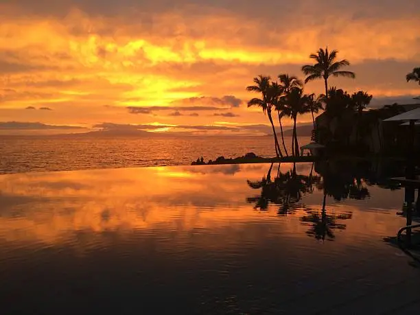Maui sun setting in infinity pool.