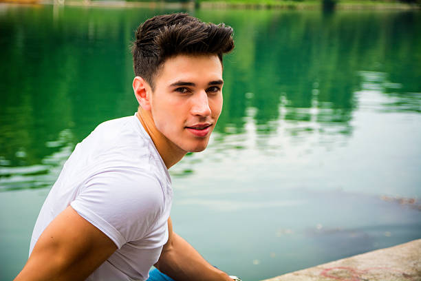 athletic man standing on city bridge over river and looking at camera.