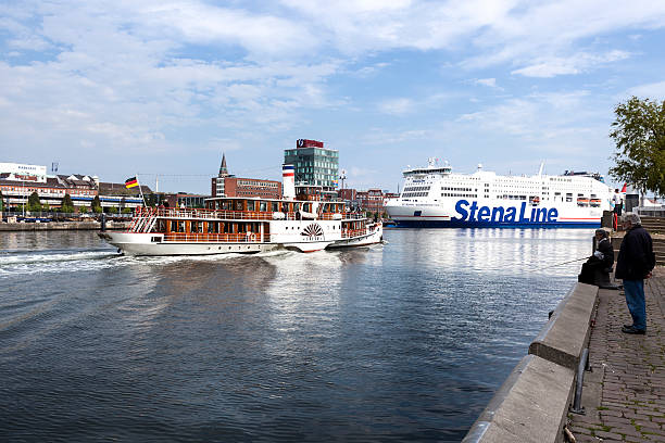 Kiel, Germany - May 20, 2012: Vintage paddlesteamer FREYA in the harbor of Kiel, Germany - observed by two anglers on the quayside. In the background a large ferryboatof swedish cruiseferry line Stena Line.