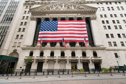 New York, USA - July 8, 2015: A giant American Flag hanging outside the famous New York Stock Exchange building early in the morning.