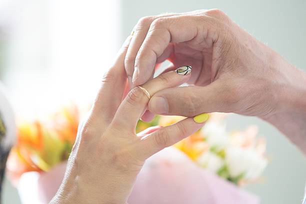 istock groom wears gold wedding ring on bride's finger 482186300
