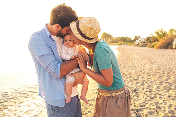 istock Loving parents kissing baby's cheeks on beach 482191615