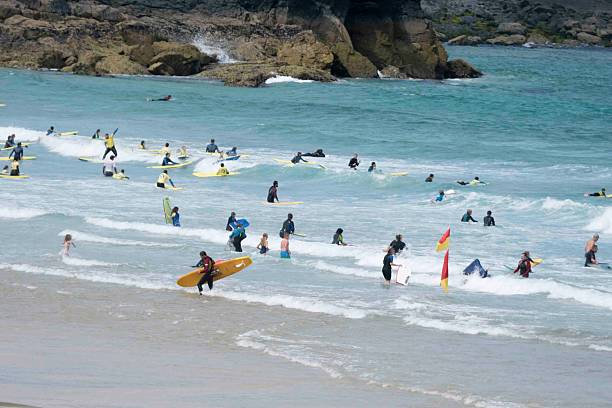 St Ives, England - July 17, 2015: Surfers and body boarders enjoying the waves at a beach in St Ives, Cornwall in summer. 