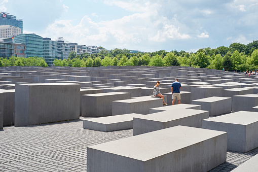 Berlin, Germany - July 8, 2015: Young couple seated on stone block at the Memorial to the Murdered Jews of Europe.