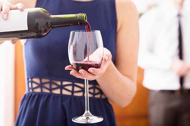 istock young woman pouring red wine into glass 482199658