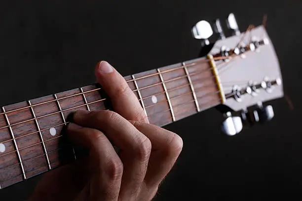 Photo of Male hand holding a barre on the guitar