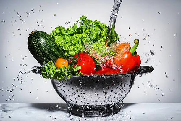 Photo of vegetables in a colander under running water