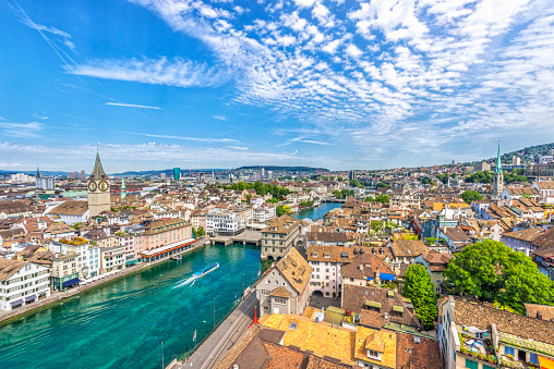 Elevated view over Zürich and the Limmat river with the landmark town hall and a ferry boat on a beautiful summer day.