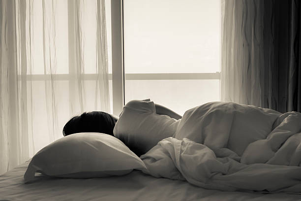 istock Young woman sleeping in bed beside the window 482212384