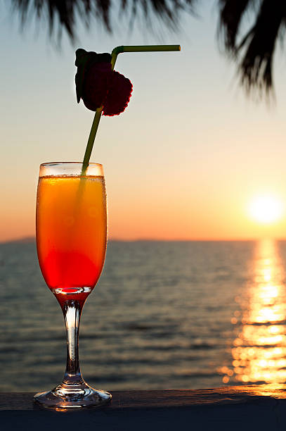 glass with cocktail and a straw against sunset