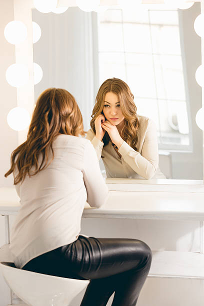 istock stylish woman looking in her reflection at mirror with bulbs 482253556