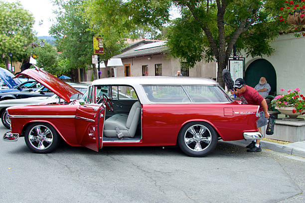 Durango, Colorado, USA - June 18, 2016: Red and orange cars at a car show, lined up on the street.  The cars are muscle and vintage cars.  Some of the cars have their hoods raised.  The paint jobs on the cars are pristine, clean and shiny.