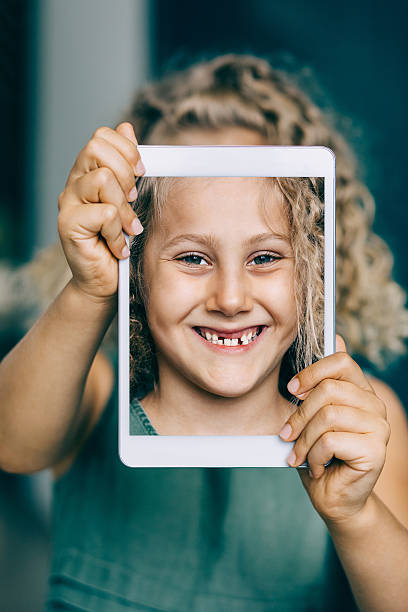 istock Smiling little girl with digital tablet making selfie 482263512