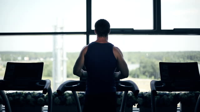 Silhouette of man running on the treadmill