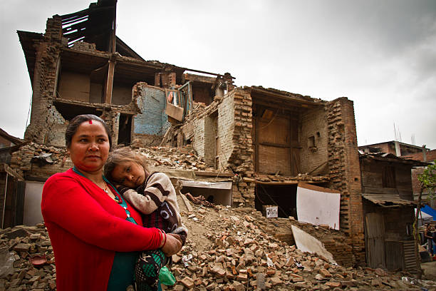 Mother and child outside earthquake ruined home, Bhaktapur, Nepal Bhaktapur, Nepal - May 9, 2015: Mother and child outside, earthquake ruined home, Bhaktapur, Nepal. Earthquake damage on the streets of Bhaktapur. Located 30km east of Kathmandu, the town was once rich with Buddhist and Hindu temples and a popular tourist spot for those visiting Kathmandu, Nepal thamel stock pictures, royalty-free photos & images