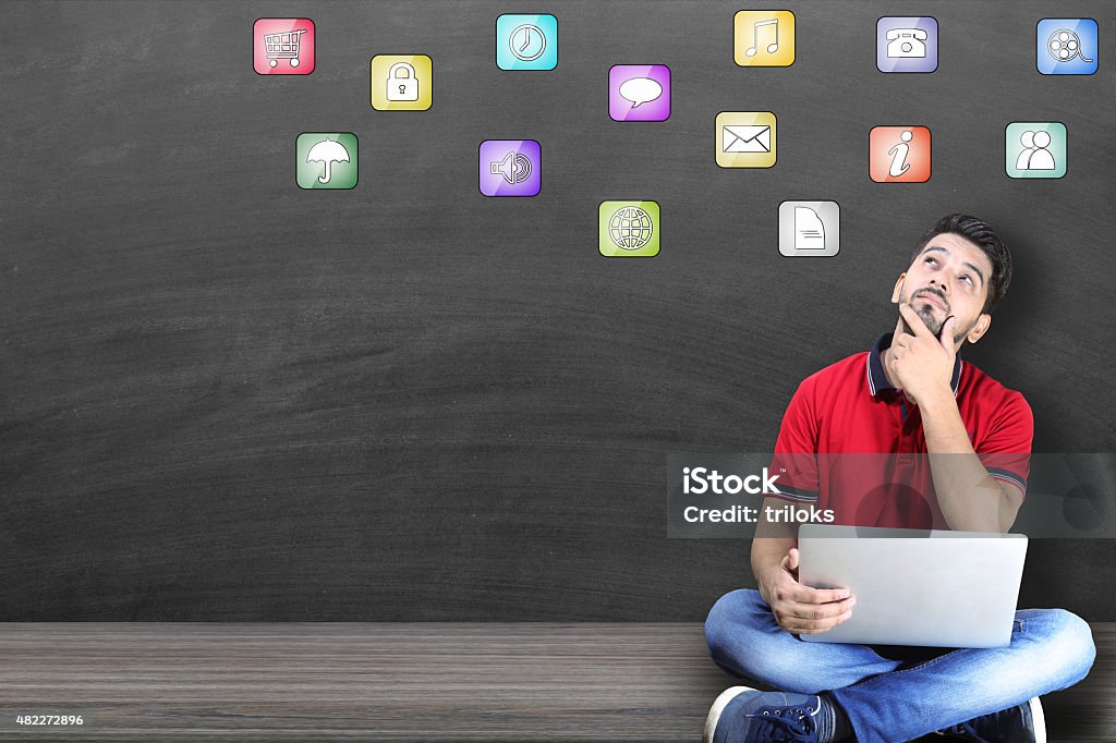 Young man thinking about new apps Young men looking up apps in blackboard background 2015 Stock Photo