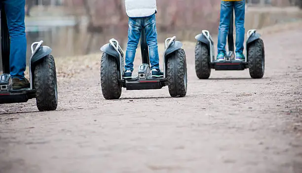 People riding segway - personal self-balancing transporters in autumn park
