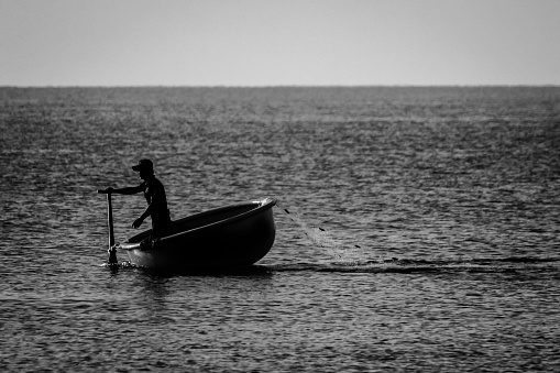 Binh Thuan, Vietnam - April 6, 2015: Man rowing a traditional Vietnamese basket boat