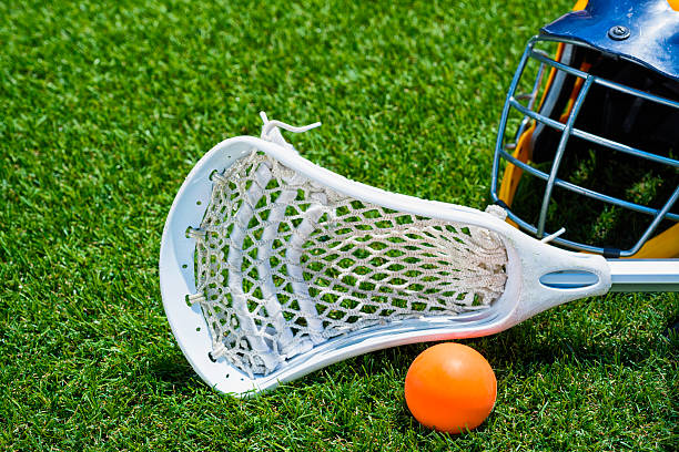 istock Orange ball, white Lacrosse stick and helmet on artificial turf 482277898