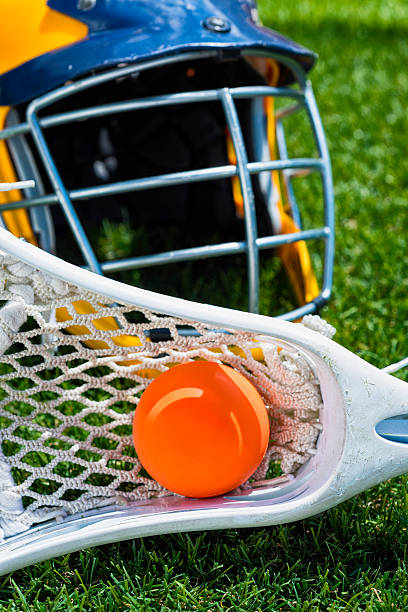 istock Orange ball, white Lacrosse stick and helmet on artificial turf 482277924