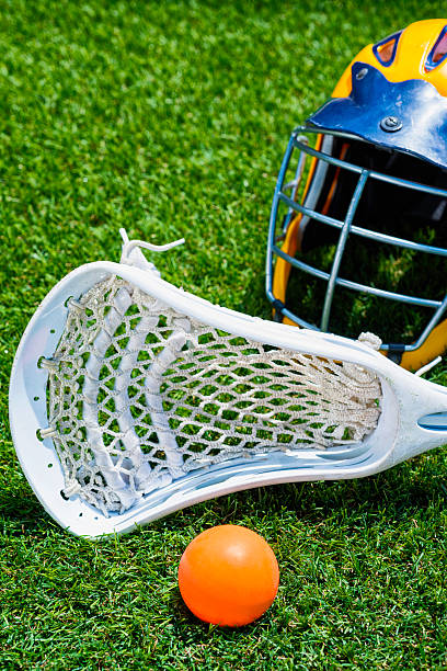 istock Orange ball, white Lacrosse stick and helmet on artificial turf 482277944