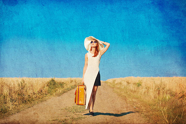 istock Redhead girl with suitcase at countryside road 482284548