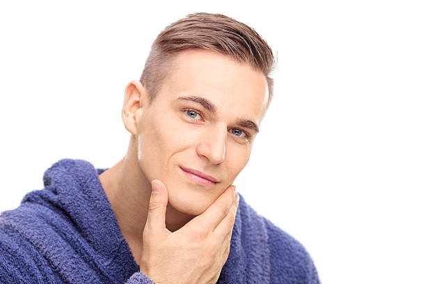 Young man checking the skin on his face Studio shot of a young man checking the skin on his face isolated on white background shaving stock pictures, royalty-free photos & images