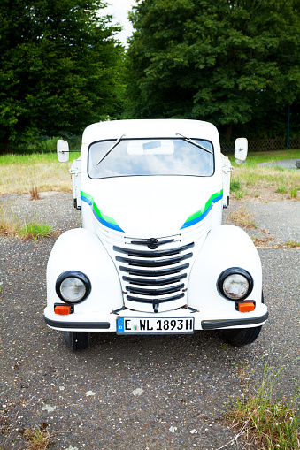 Essen, Germany - June 14, 2015: Capture of a white small oldtimer pick-up car standing close to a field in south of Essen, Ruhrgebiet. Maybe kind of Chevrolet or other brand.