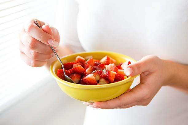istock Woman holding fresh strawberries in a bowl 482300117