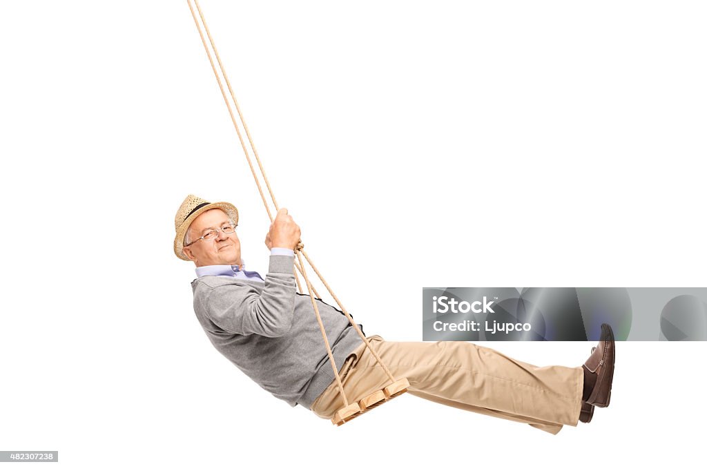 Carefree senior man swinging on a wooden swing Carefree senior man swinging on a wooden swing and looking at the camera isolated on white background Using A Swing Stock Photo