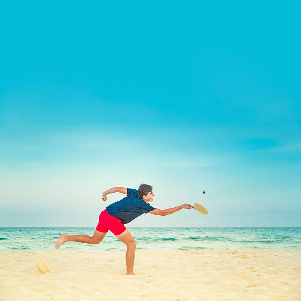 Beach Tennis Teenager playing tennis/paddle ball in the beach paddle ball stock pictures, royalty-free photos & images