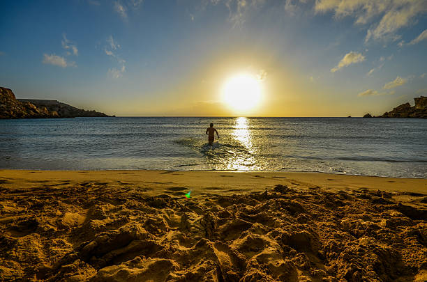 junger mann läuft während des sonnenuntergangs mit wasser - golden bay stock-fotos und bilder