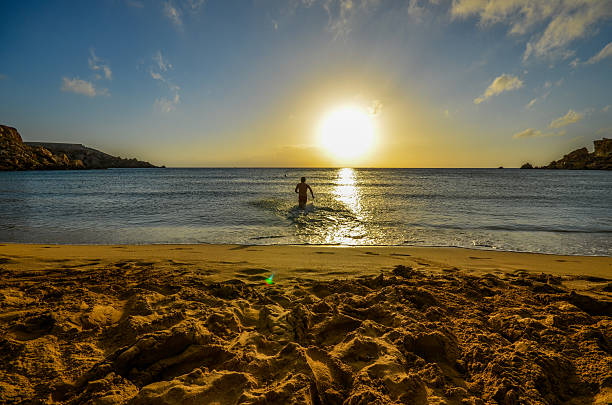 Young man running into water during the sunset on the calm late afternoon summer day, excited and stressless in search of happiness and freedom.
