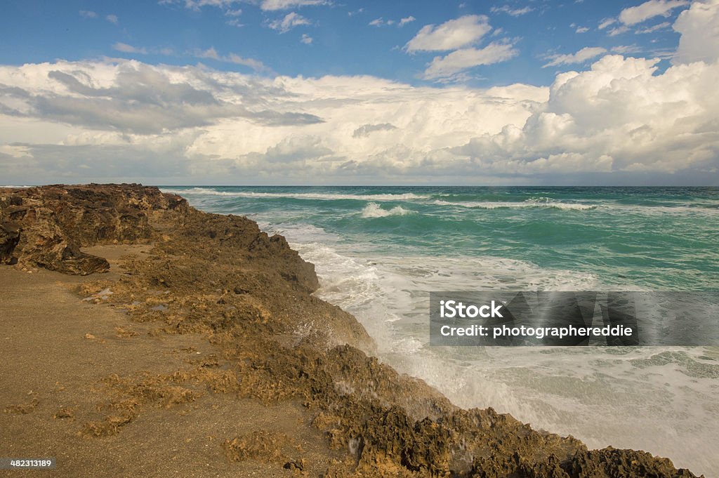 Hutchinson Island Geological Formation Anastasia formation on a Florida Beach with amazing colored water and blue sky half covered with white clouds. Beach Stock Photo
