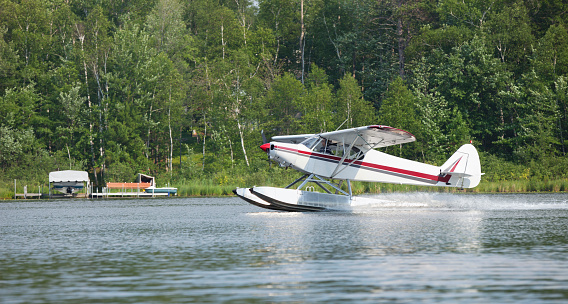 A small white floatplane lands on a Minnesota lake in summer