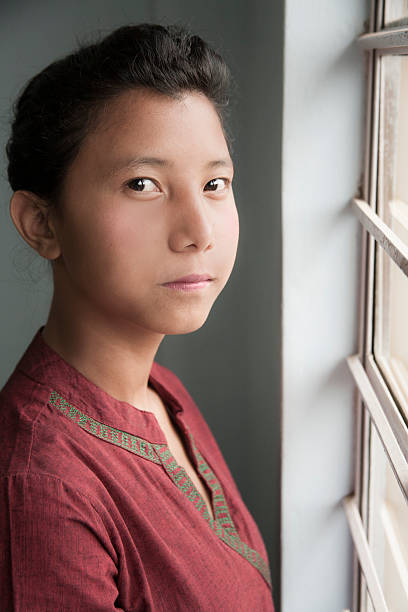 istock Pretty Asian descent girl standing at home window. 482342022