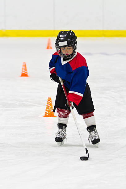 istock Boy skating with the puck at ice hockey practice 482342113