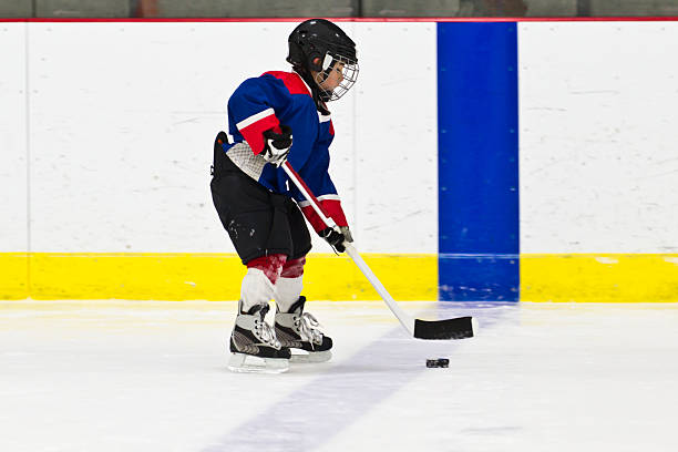 istock Boy skating with the puck at ice hockey practice 482342153