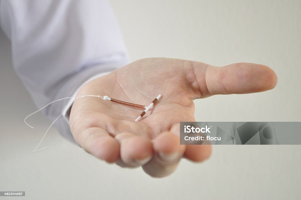 Holding an IUD birth control device in hand Holding an IUD birth control copper coil device in hand, used for contraception - front view IUD Stock Photo