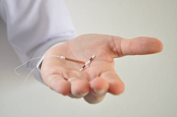Holding an IUD birth control device in hand Holding an IUD birth control copper coil device in hand, used for contraception - front view contraceptive photos stock pictures, royalty-free photos & images