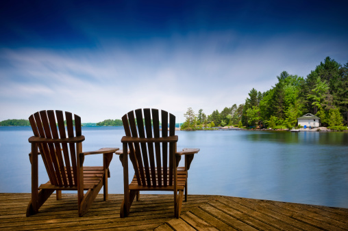 Wood Muskoka chairs on a lake deck