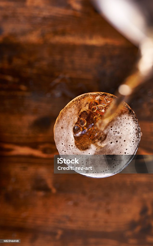 pouring beer into glass top down pouring beer into glass top down on top of wooden table 2015 Stock Photo