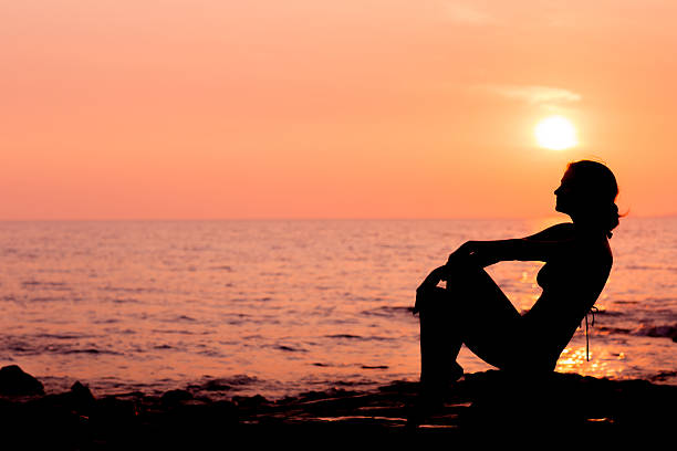 istock Woman silhouette sitting on sea background back lit 482352290