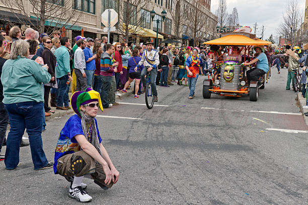Asheville, North Carolina, USA - March 2, 2014: Downtown Aseville Mardi Gras parade with crowds, a Fool, a unicyclist and the PubCycle on March 2, 2014 in Asheville, NC