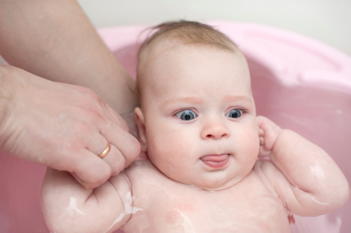 Little beautiful blue-eyed baby taking a bath