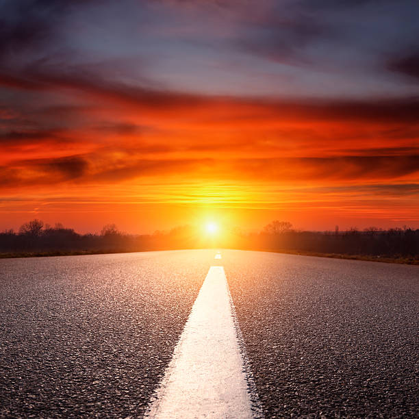 istock Driving on an empty asphalt highway towards the setting sun 482355133
