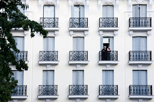Madrid, Spain - september 21, 2010: senior couple on a cast iron balcony, in the facade of a vintage apartment building seen from the street in downtown Madrid, Spain.