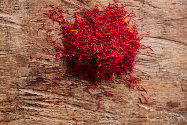 istock saffron spice in pile on old wooden background, closeup 482360118